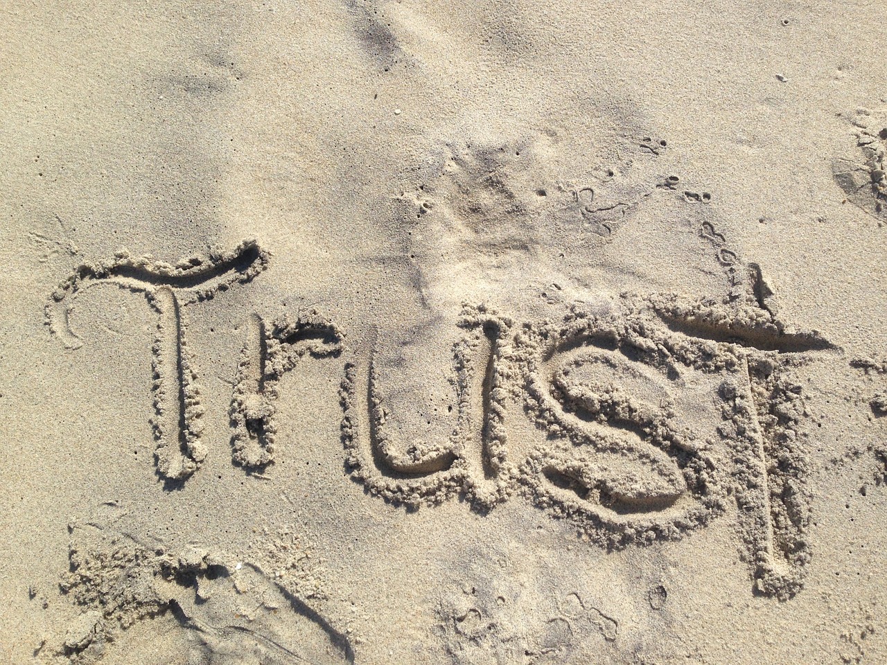 the word trust written in sand